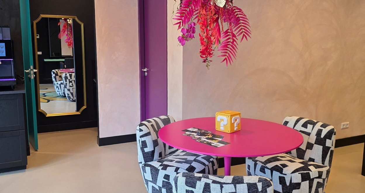 Ontvangst met een roze ronde tafel, zwart-witte fauteuils en roze bloemen aan het plafond